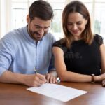 Comment changer de nom après mariage : quelles démarches faut-il suivre couple-signant-documents-de-mariage-heureux