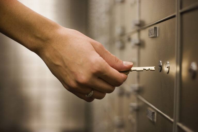 Comment Louer Un Coffre-Fort À La Banque Postale Pour Sécuriser Ses Biens 2 main deposant cle dans coffre fort bancaire securise